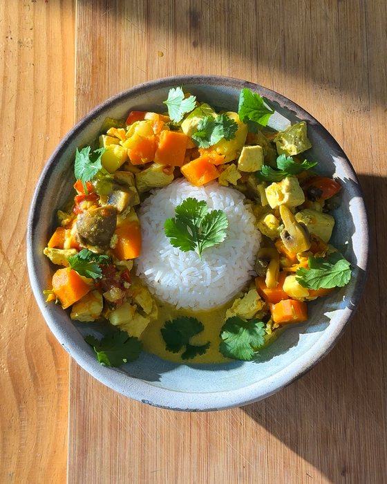 Tofu, mushroom and sweet potato curry served with rice and fresh cilantro.