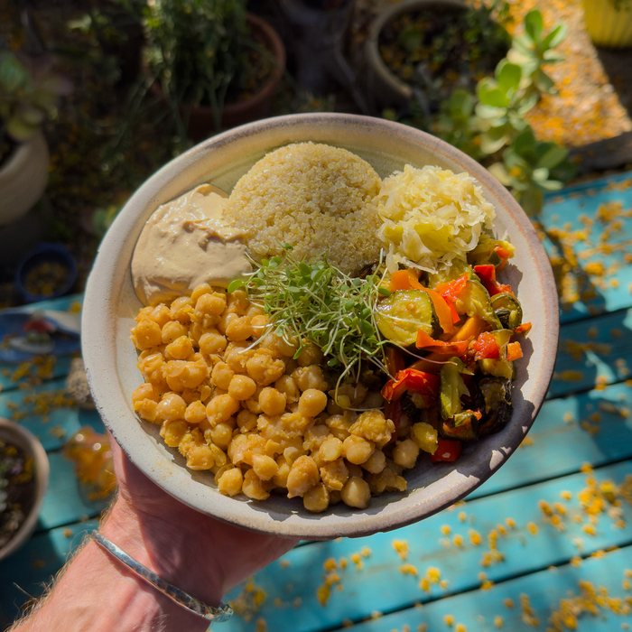A chickpea and quinoa bowl with roasted vegetables, tahini, sauerkraut and sprouts.