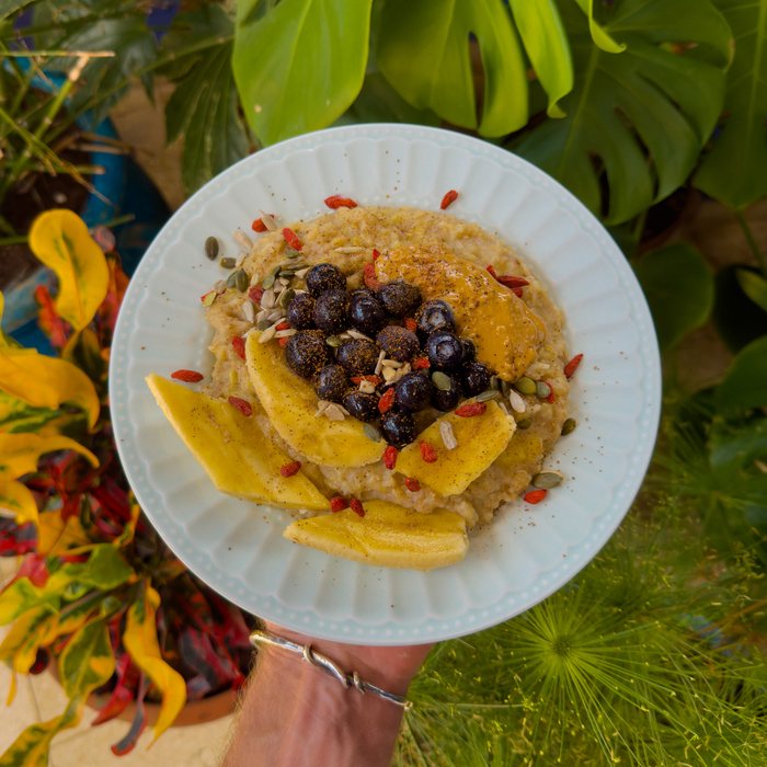 A bowl of ginger oats topped with banana, blueberries, goji berries and pumpkin seeds.
